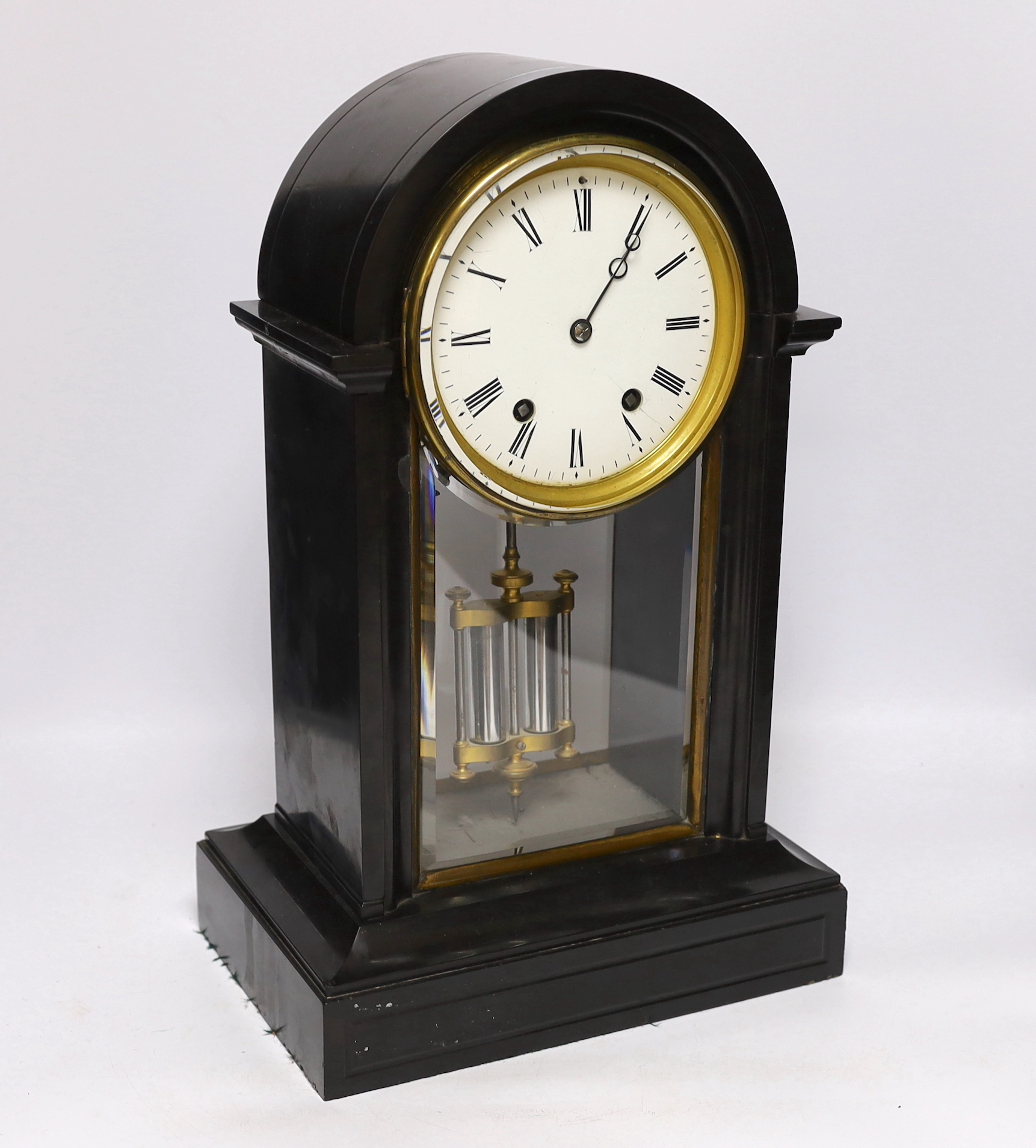 A slate cased domed mantle clock, with enamelled dial striking on a bell, with black Roman numerals above a bevelled glazed trunk with mercury style pendulum, 46cm